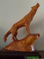 Side view of the carved wooden wolf howling on rock base, showing detailed fur carving and smooth finish.