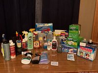 Photo of entire cleaning supplies lot on table showing all items arranged in front of dark curtain background.