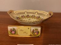 Photo showing the 14 inch bowl with reticulated edge and the Love Story retail plaque with decorative panels and gold trim