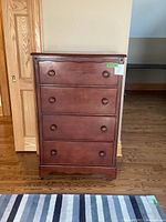 Front view of the maple highboy dresser showing four drawers with wood knobs and reddish-brown finish.