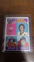 Full front view of the 1974-75 Bobby Orr Assist Leaders hockey card featuring three players with text.