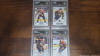 Four Connor McDavid rookie hockey cards in plastic protective cases graded GMA 10 arranged on wooden surface