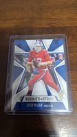 Front view of Josh Allen football trading card in protective case showing player in red Bills uniform with star background and 'Rookies & Stars' title.
