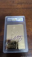 Front of the 1996-97 Fleer Kobe Bryant 23KT Gold Rookie card graded 10 GEM-MT by WCG showing Kobe shooting with purple autograph and gold finish.