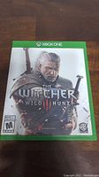 Front cover of The Witcher Wild Hunt III Xbox One game case showing main character Geralt.