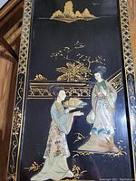 Close-up of one wall hanging panel showing detailed shell inlay of Chinese women and gold painted landscape on black lacquer background with decorative border.