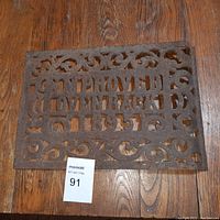 Top view of rectangular cast iron grate with decorative scrollwork and text 'IMPROVED LOVENRACK'
