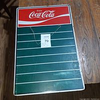 Front view of the Coca-Cola sign with logo and chalkboard area with hanging string.