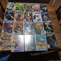 Photo showing 21 Justice League of America and Justice Society comic books arranged on a wooden table, clear front cover views with vibrant cover illustrations of superheroes.
