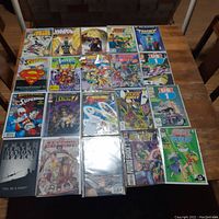 Top-down view of 20 comic books on a wooden table displaying colorful superhero covers including Superman and Justice League.