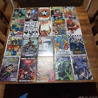 Full top-down photo of all 20 comic books laid on a wooden table in 4 rows