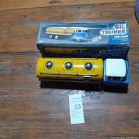 Top-down photo of the yellow and blue friction oil tanker toy with original box placed on a wooden surface.