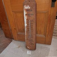 Full view of rusty vintage metal thermometer beer sign with brand and slogan visible.