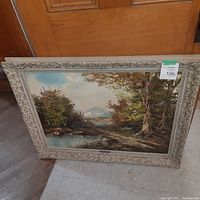 Full view of the framed landscape painting showing overall condition and setting.