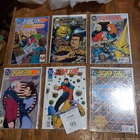 Photo showing all six Star Trek: The Next Generation comics with varied covers placed on a wooden surface.