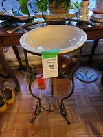 Front view of vintage metal wash stand with ceramic bowl placed inside the frame.