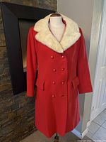 Front view of the red wool peacoat with cream fur collar, double-breasted button front with one button missing.