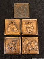 Close-up of four plaques including squirrel with birds, horse, spaniel dog, and birds on branch; individual plaque details visible