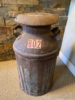 Full front view of antique milk can showing body shape, rust and number 802 label.
