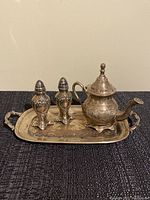 Front view of the full set against a dark textured surface highlighting the fine detailed engraving on all items.