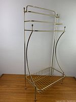 Brass towel rack blanket holder shown empty on wooden surface with white background
