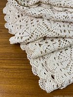 Closeup photo showing the detailed crochet stitching and scalloped edge of the vintage table cloth