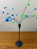 Front view of Laurids Lonborg atomic ball table mobile sculpture showing wide spread of blue and green spheres on metal rods from single black base.