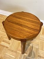 Top view showing circular teak wood tabletop with visible grain patterns and round edge detail.