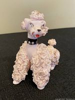 Front and side views of the pink porcelain poodle figurine with jeweled eyes and collar, showing detailed spaghetti style textured fur and gold flake accents.