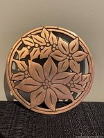 Full front photo of the round vintage copper trivet with poinsettia flower design