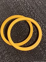 Two yellow Bakelite bangles on a black textured surface.