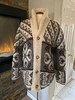 Front view of the knit button-up sweater jacket showing wood buttons, shawl collar, geometric and floral knit patterns in beige, gray, and brown.