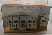 Box showing KitchenArt Select-A-Spice Auto-Measure Carousel spice dispenser with 12 containers and carry handle