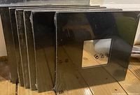 Six black square IKEA Malma mirrors sealed in original plastic, showing they are unused and new.