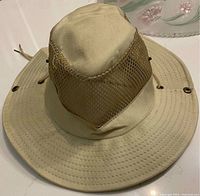 Front and side view of beige sun hat with mesh ventilation panels and wide brim.