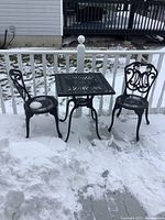Overall view of square table and two chairs on snow-covered deck