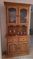 Front view of solid wood cabinet with glass doors, drawers, cupboard, and glass top.