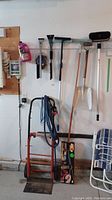 Full view of the wall showing the shovel, snow brushes, squeegees, and four wheel dolly with blue coiled hose