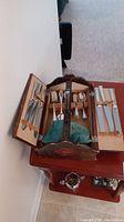 Opened wooden canteen showing organized silver plate flatware for six people with compartments and leather straps