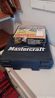 Photo of closed Mastercraft blue carrying case and Arrow staple gun kit, boxed, on top of case.