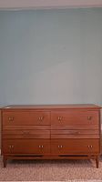 Front view of six-drawer dresser showing warm wood finish and bronze color handles