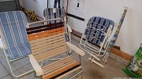 Five folding lawn chairs, metal framed with fabric seats in blue and brown striped patterns