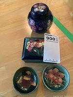 All four pieces displayed on wood surface: lidded jar, rectangular box and two bowls, top view.