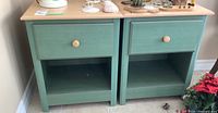 Pair of two matching light green nightstands with laminate wood tops and one drawer each shown from front and side angles.