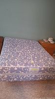 Queen size mattress and boxspring set displayed with floral patterned fabric, shown from front