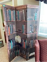 Three-panel folding room divider resembling bookshelves with books, a globe, and an old telephone printed on panels.