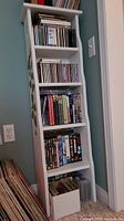 Full view of white wooden shelf filled with books and CDs, showing overall structure and size
