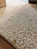 Close up image showing the looped Berber style weave and some wear spots on the rug.