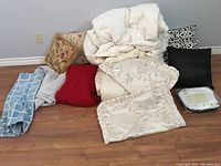 Overview of all bedding lot items including comforter, various pillows and folded bedding pieces