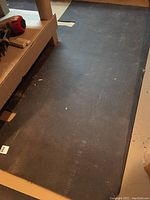 Long black rubber mat on floor beneath shelving, showing general wear and some dirt.